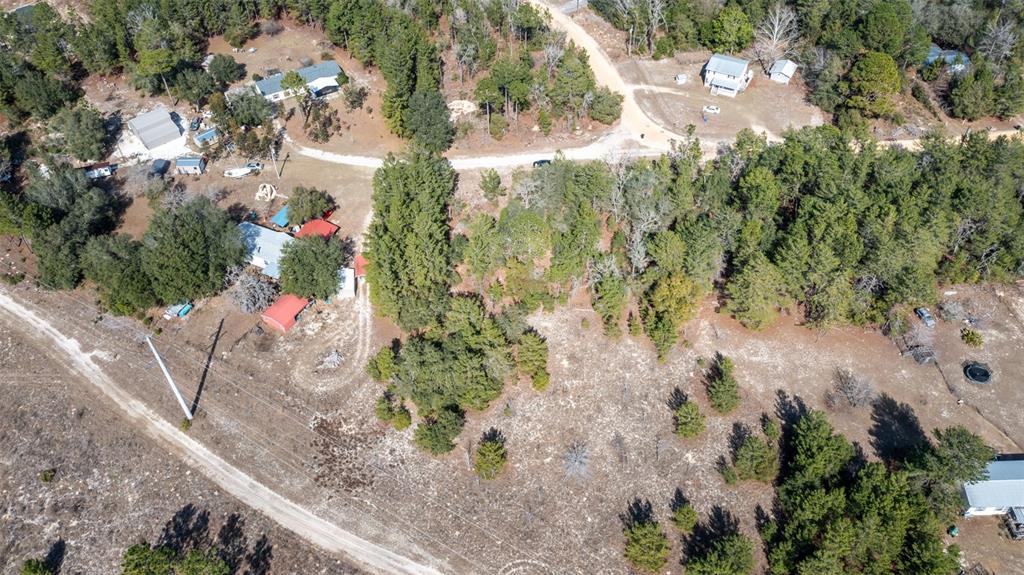 An aerial view shows several houses surrounded by trees and dirt roads in a rural area — 5851 HILLRIDGE ROAD, KEYSTONE HEIGHTS, FL