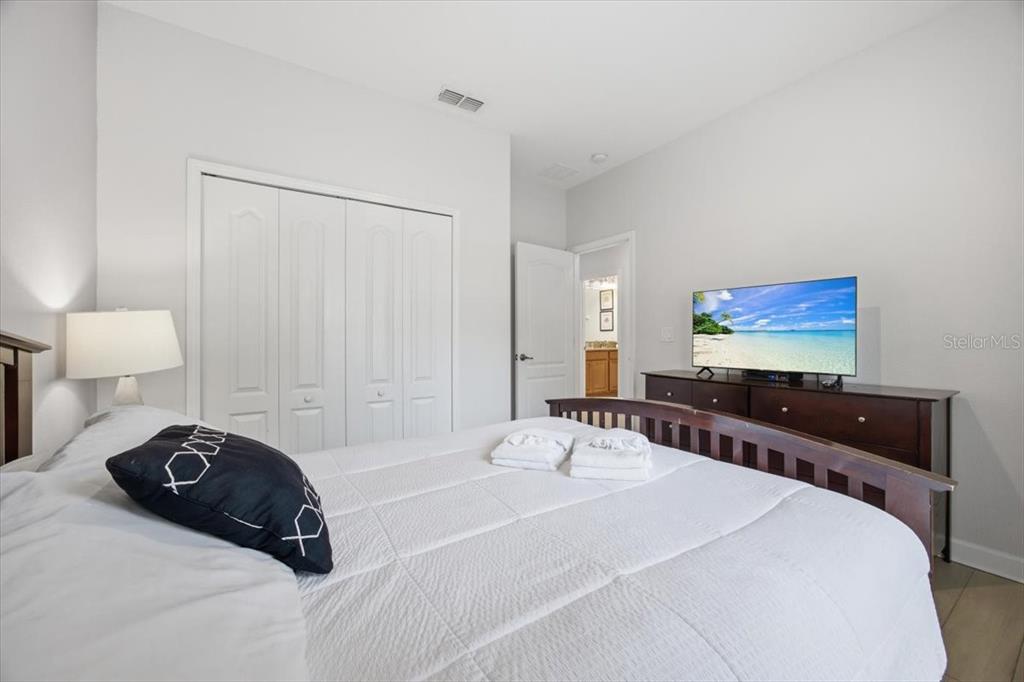 A bedroom features a bed with white bedding, a dark wood dresser, and a closet — 8922 CUBAN PALM ROAD, KISSIMMEE, FL