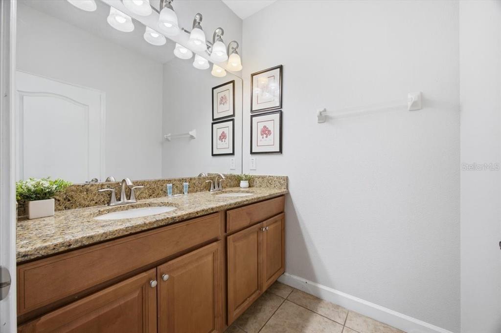 A bathroom features a double-sink vanity with granite countertops and a large wall mirror — 8922 CUBAN PALM ROAD, KISSIMMEE, FL