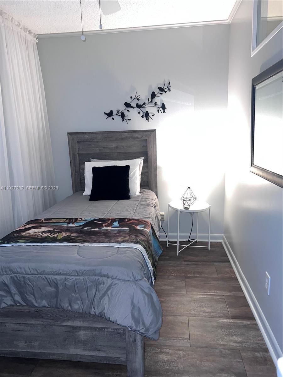 A bedroom features a twin bed with gray bedding, a small side table, and wall decor — 4740 NW 21st St # 4P, Lauderhill FL 33313, LAUDERHILL, FL