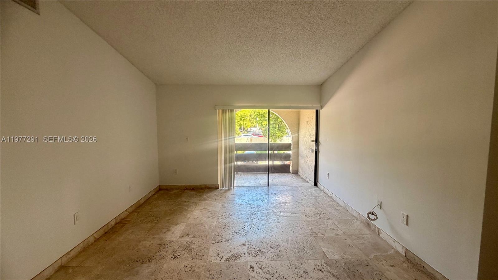An empty room features light-colored stone tile flooring and a sliding glass door to a balcony — 8811 SW 123rd Ct # 1, Miami FL 33186, MIAMI, FL