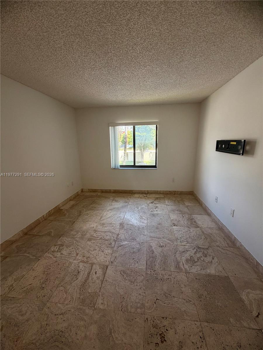 An empty room features light-colored stone tile flooring, white walls, and a single window — 8811 SW 123rd Ct # 1, Miami FL 33186, MIAMI, FL