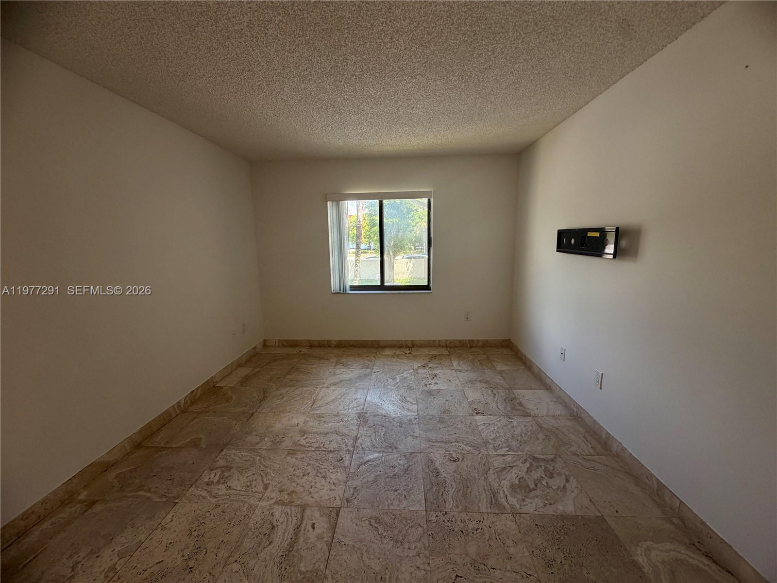 An empty room features beige tile flooring, white walls, and a single centered window — 8811 SW 123rd Ct # 1, Miami FL 33186, MIAMI, FL