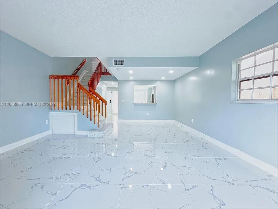 A bright living room features white marble-patterned tile floors and a wooden staircase — 10014 Hammocks Blvd # 4, Miami FL 33196, MIAMI, FL