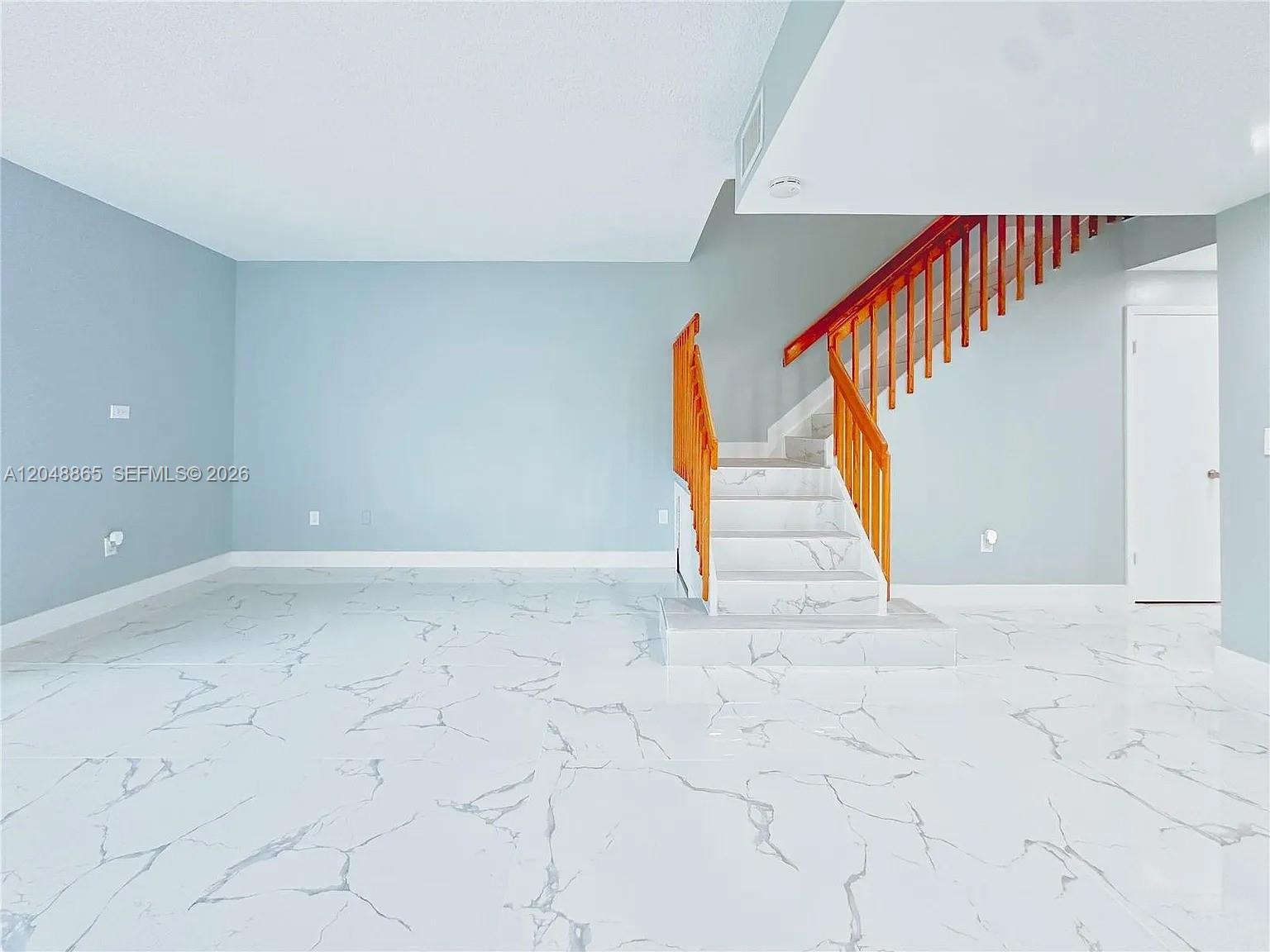 A room with light blue walls, white marble-patterned tile floors, and a wooden staircase — 10014 Hammocks Blvd # 4, Miami FL 33196, MIAMI, FL
