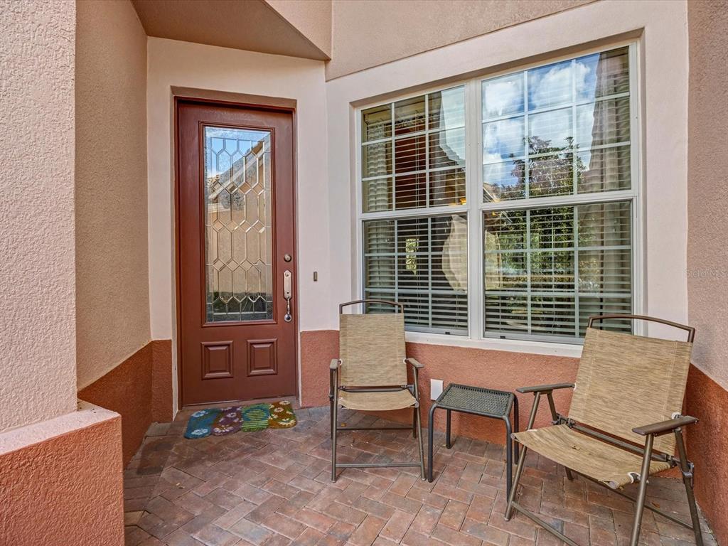 A patio with two chairs, a small table, a front door, and a large window — 1405 LISBON COURT, DAVENPORT, FL