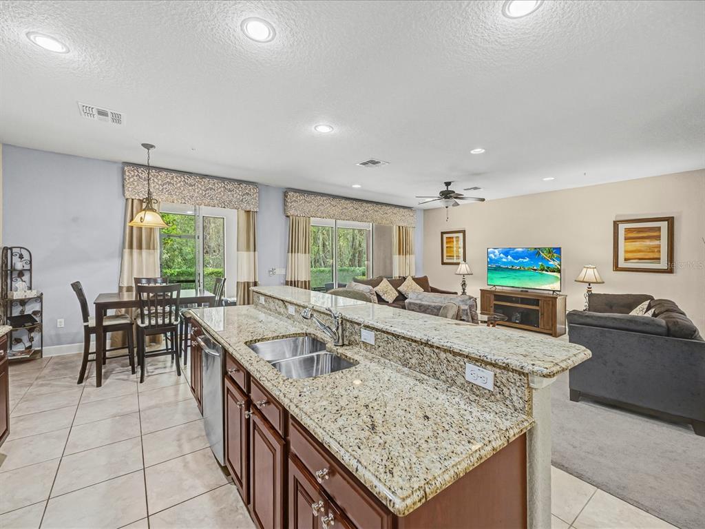 A kitchen island with granite countertops overlooks an open-concept living and dining area — 1405 LISBON COURT, DAVENPORT, FL