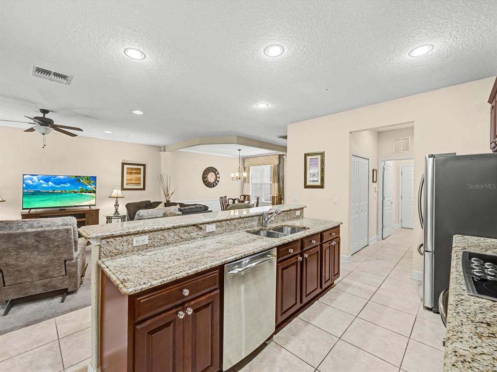 A kitchen with granite countertops and dark wood cabinets overlooks an open-concept living room — 1405 LISBON COURT, DAVENPORT, FL