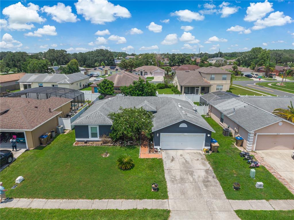 An aerial view shows a single-story house with a gray exterior, two-car garage, and lawn — 5121 HEATHERSTONE COURT, KISSIMMEE, FL