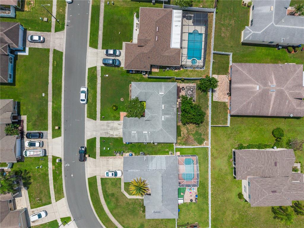 An aerial view shows several suburban houses with swimming pools and driveways along a street — 5121 HEATHERSTONE COURT, KISSIMMEE, FL
