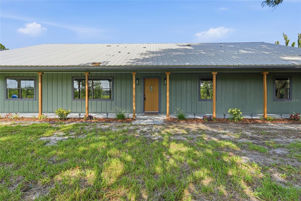 A single-story house with green vertical siding, a metal roof, and a covered front porch — 4351 NE 210TH AVENUE, WILLISTON, FL