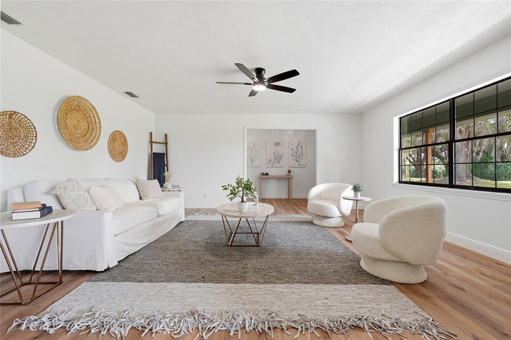 A bright living room features a white sofa, two armchairs, and a large area rug — 4351 NE 210TH AVENUE, WILLISTON, FL
