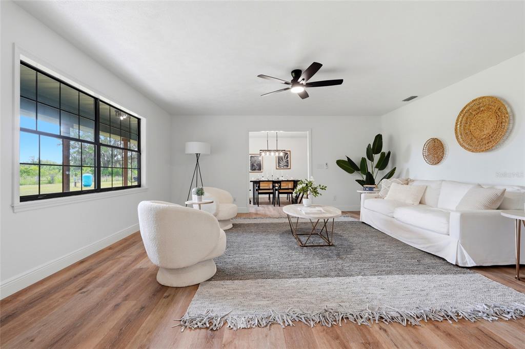 A bright living room features white walls, wood flooring, a large area rug, and furniture — 4351 NE 210TH AVENUE, WILLISTON, FL