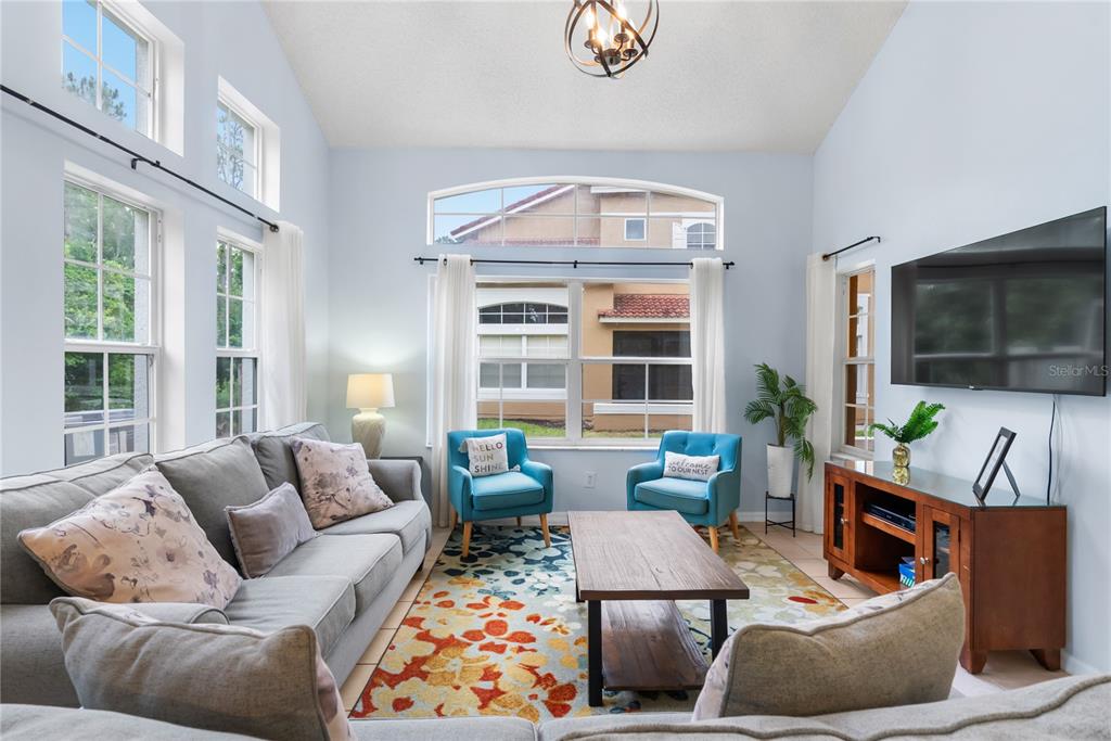 A living room features a vaulted ceiling, a colorful area rug, and two blue armchairs — 2733 SUN KEY PLACE, KISSIMMEE, FL