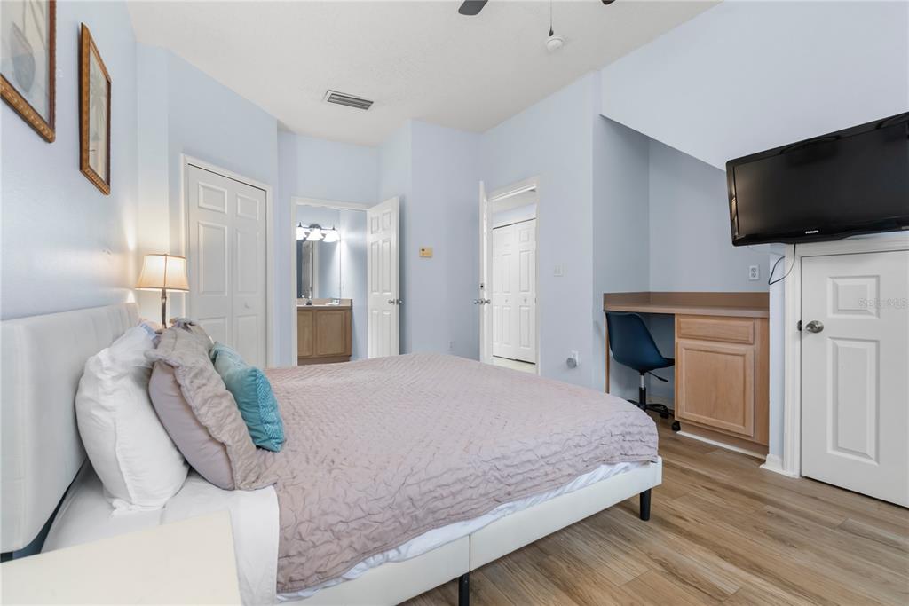 A bedroom features a bed, a built-in desk, light blue walls, and wood-look flooring — 2733 SUN KEY PLACE, KISSIMMEE, FL