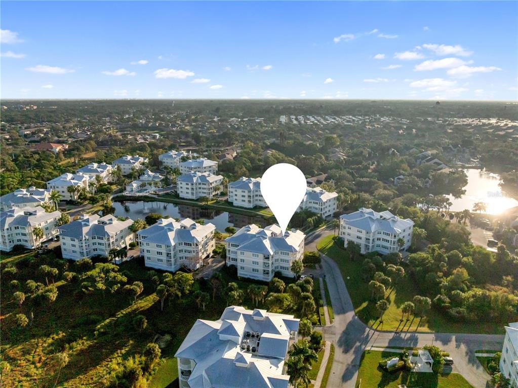 An aerial view shows multiple multi-story residential buildings surrounding a small lake — 7840 34TH AVENUE W UNIT 103, BRADENTON, FL