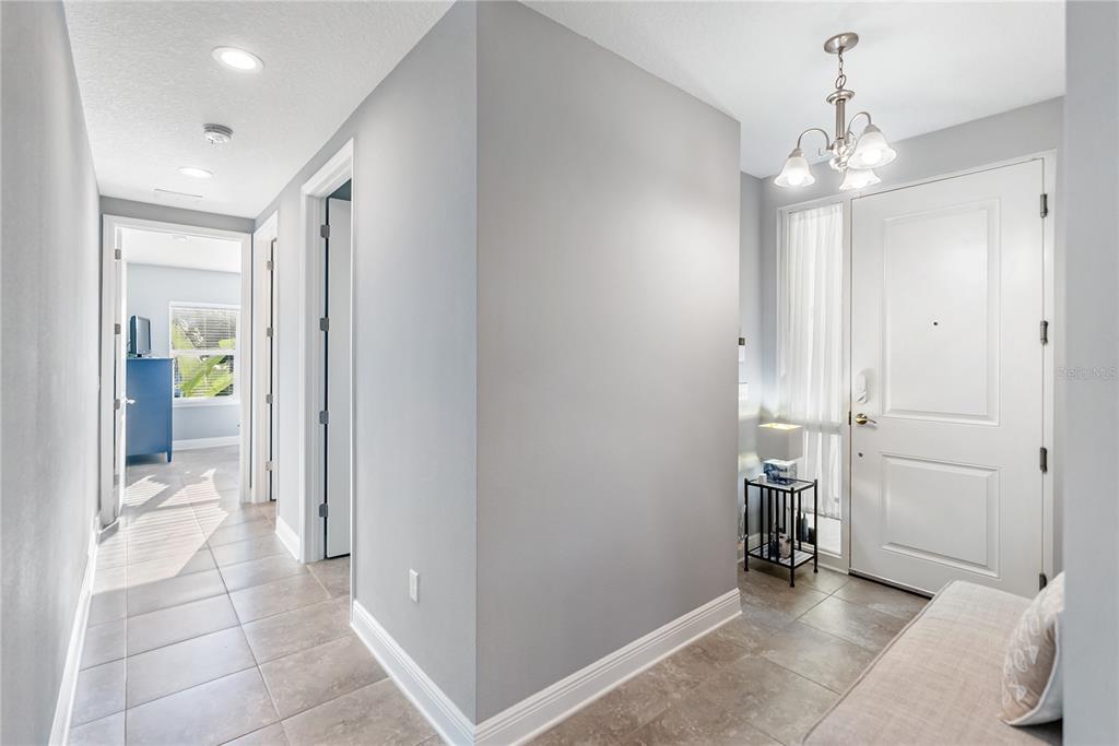 An entryway with light gray walls, tile flooring, a white front door, and a chandelier — 7840 34TH AVENUE W UNIT 103, BRADENTON, FL