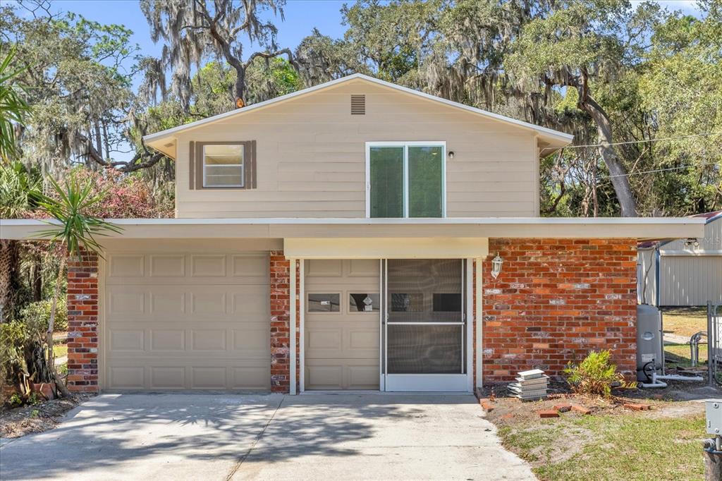A two-story house with a brick facade, a garage, and a screened front entryway — 1610 GLENWOOD ROAD, DELAND, FL