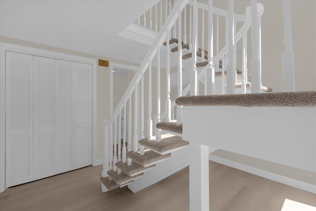 A staircase with carpeted treads and white railings stands in a room with light flooring — 1610 GLENWOOD ROAD, DELAND, FL