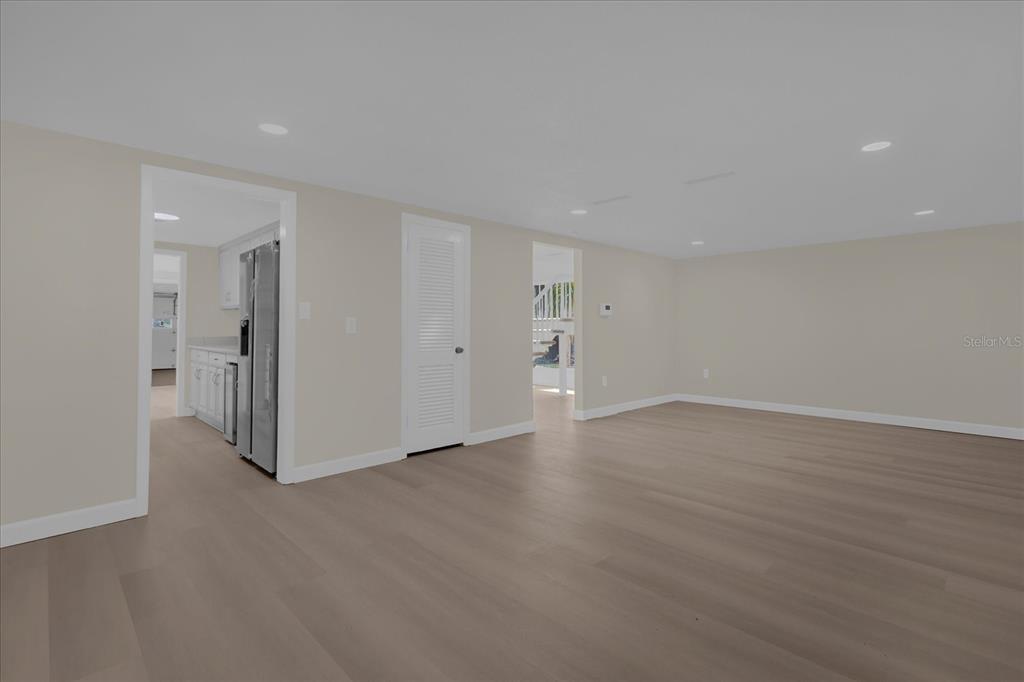 A spacious room with light wood flooring, recessed lighting, and doorways leading to other areas — 1610 GLENWOOD ROAD, DELAND, FL