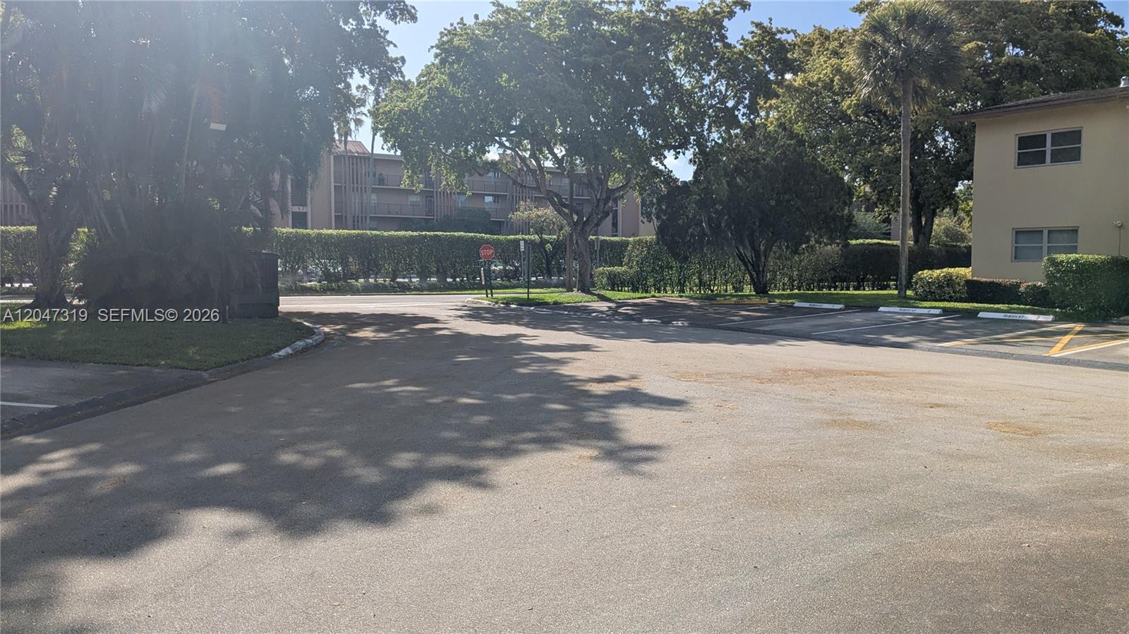 An asphalt parking lot sits in front of a multi-story apartment building with trees — 481 NW 76th Ave # 207, Margate FL 33063, MARGATE, FL