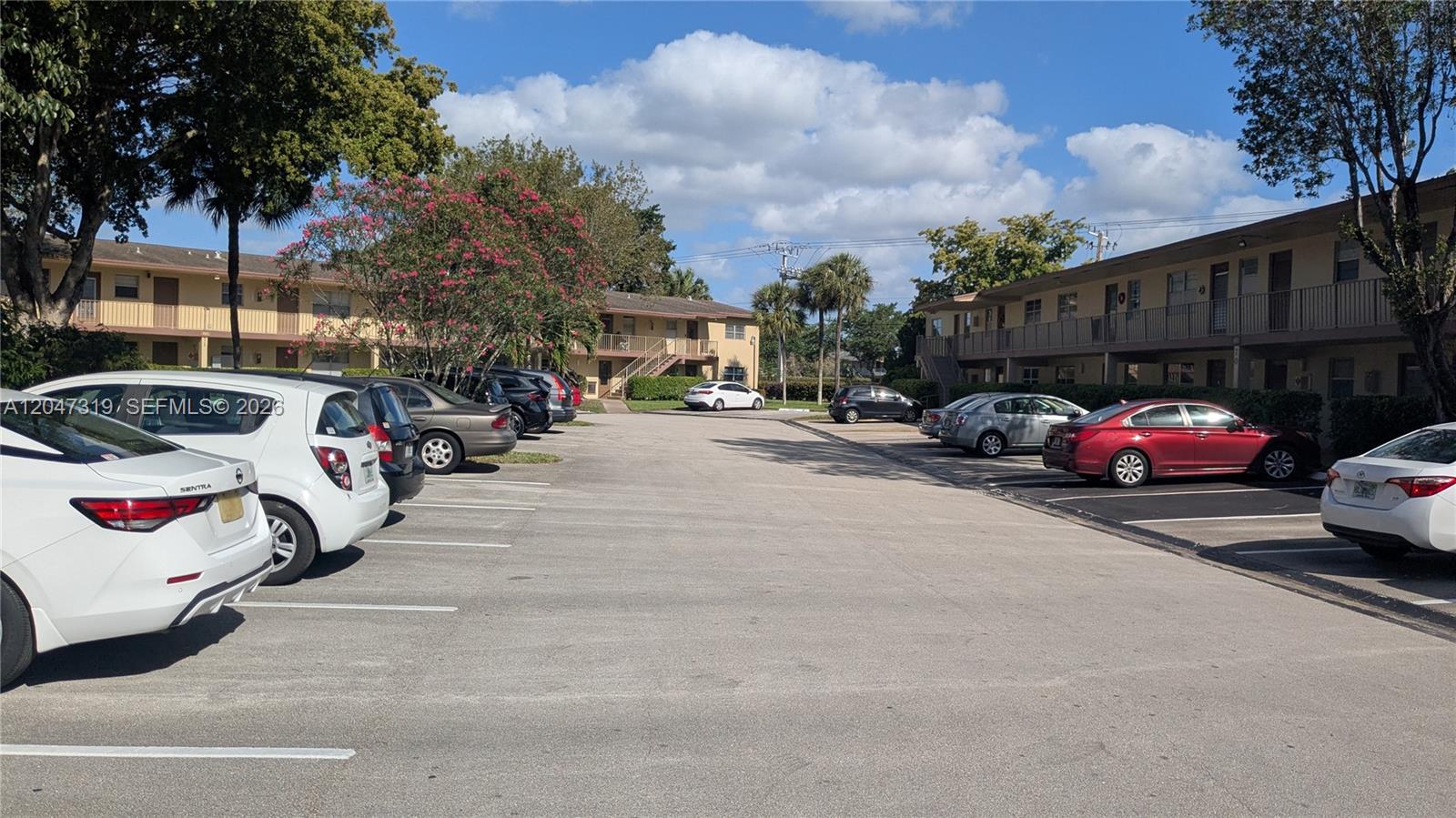 An outdoor parking lot is situated between two multi-story apartment buildings with balconies — 481 NW 76th Ave # 207, Margate FL 33063, MARGATE, FL