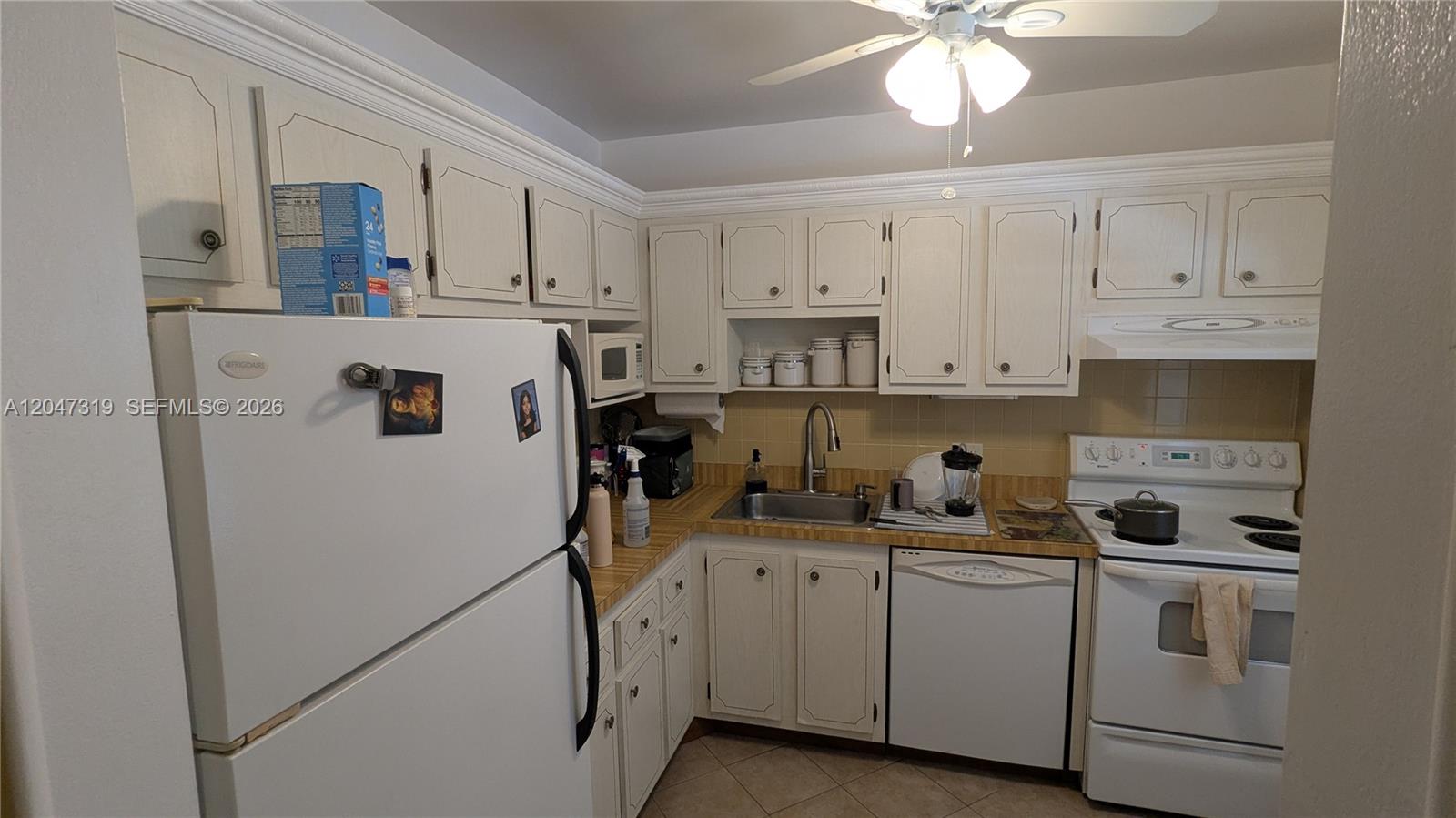 A kitchen features white cabinets, white appliances, a stainless steel sink, and tan countertops — 481 NW 76th Ave # 207, Margate FL 33063, MARGATE, FL