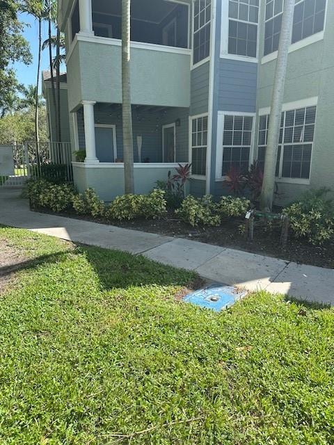 A multi-story apartment building exterior features light green siding, a screened balcony, and landscaping — 1000 Crystal Way # A, Delray Beach FL 33444, DELRAY BEACH, FL