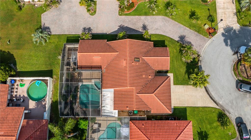 An aerial view shows a house with a red tile roof and two screened pools — 8176 TERRAZA COURT, ORLANDO, FL