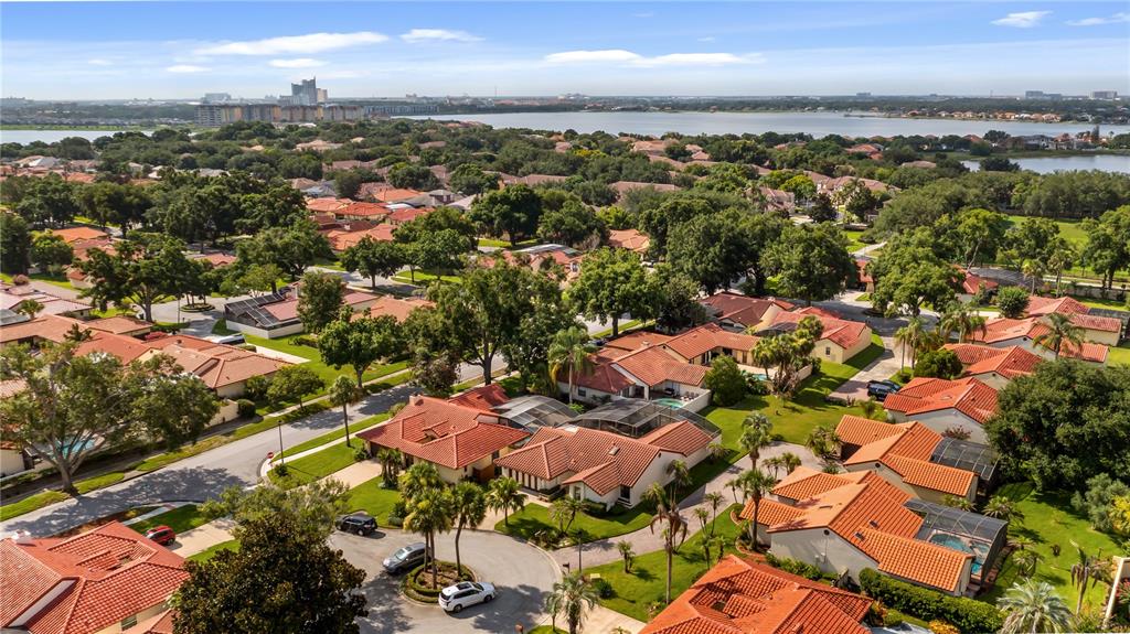 An aerial view shows a suburban neighborhood with terracotta-roofed houses and a large lake — 8176 TERRAZA COURT, ORLANDO, FL