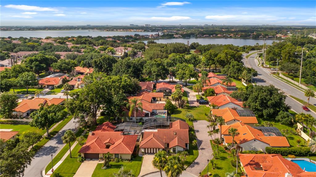 An aerial view of a suburban neighborhood with red-tiled roofs and a nearby lake — 8176 TERRAZA COURT, ORLANDO, FL