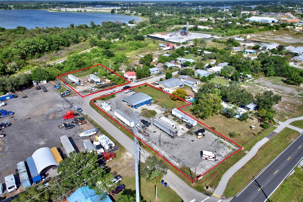 An aerial view shows two fenced industrial lots with trailers, a warehouse, and parked vehicles — 1087 MEMORIAL DRIVE, AVON PARK, FL