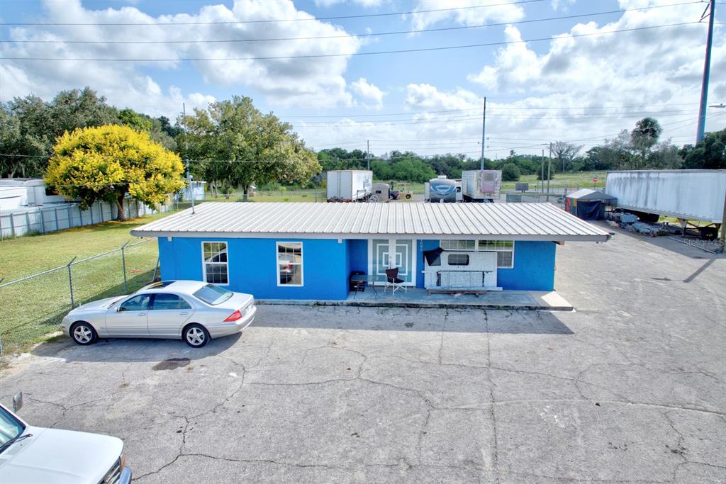 A bright blue, single-story building with a metal roof sits on a large paved lot — 1087 MEMORIAL DRIVE, AVON PARK, FL