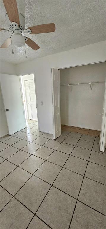 A room with light-colored tile flooring, a ceiling fan, and an open closet — 12048 HENLEY AVENUE UNIT A & B, PORT CHARLOTTE, FL