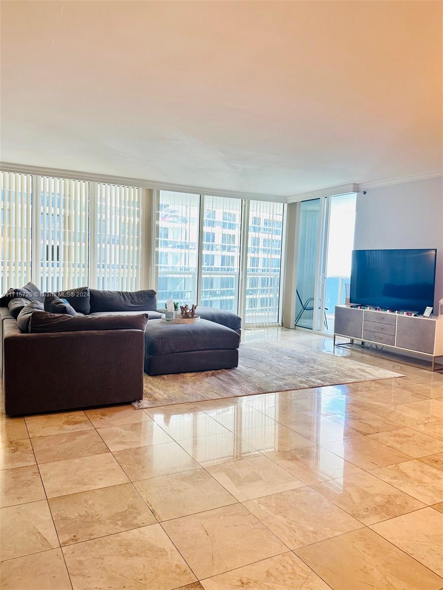A living room features a large gray sectional sofa, a television on a console, and marble flooring — 1850 S Ocean Dr # 3310, Hallandale Beach FL 33009, HALLANDALE BEACH, FL