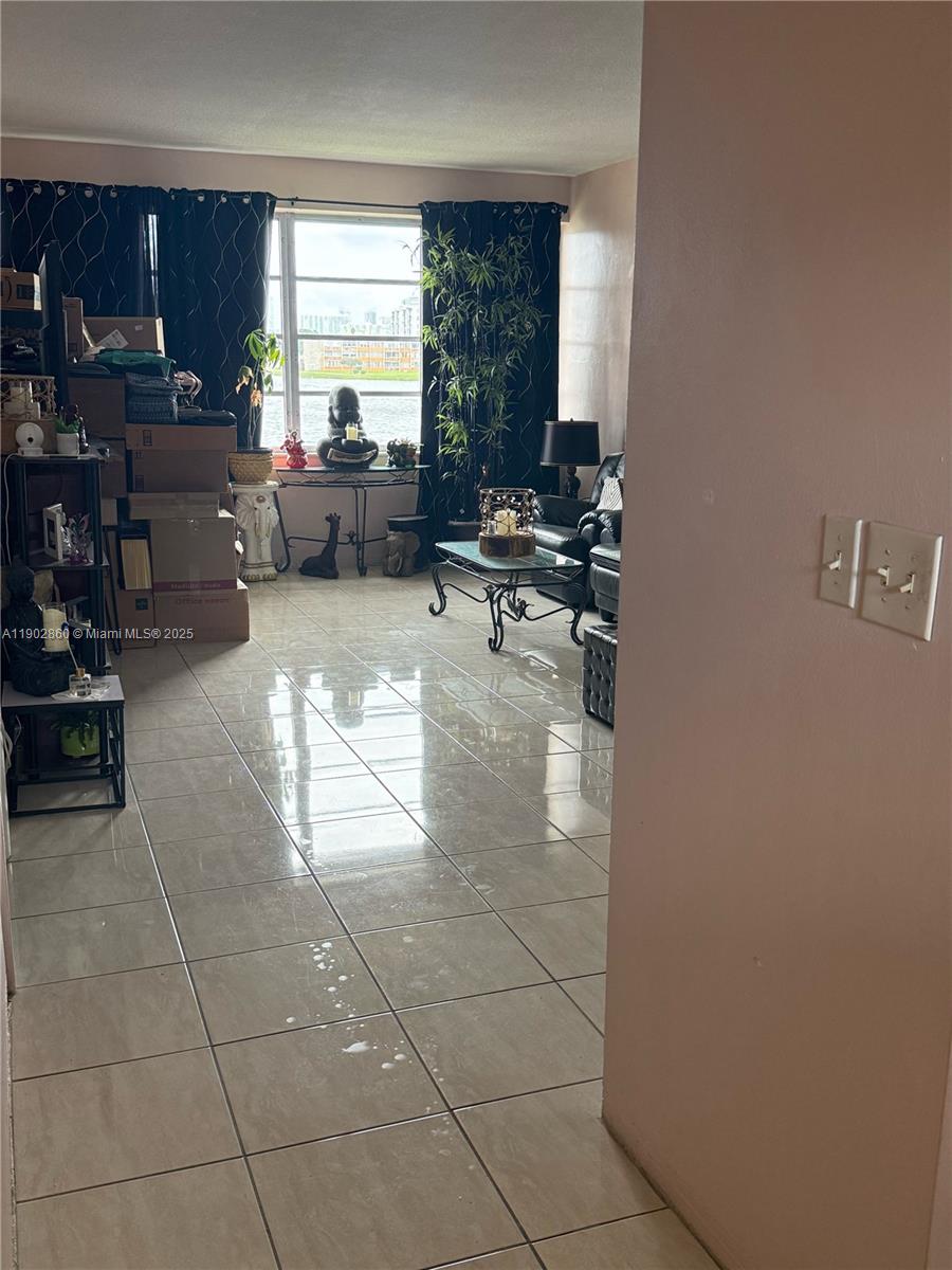 A living room with tiled floors, a large window, and stacked cardboard boxes — 18555 NE 14th Ave # 715, Miami FL 33179, MIAMI, FL