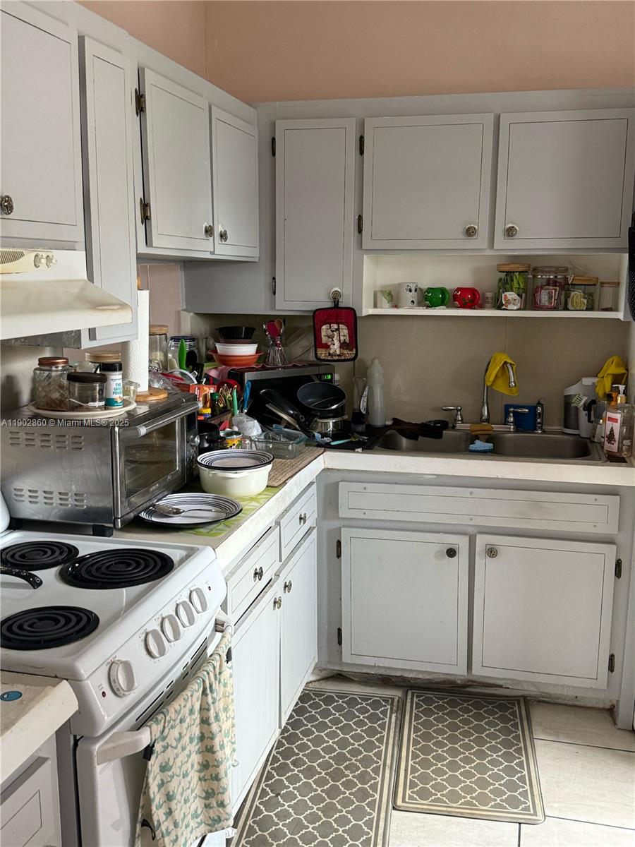 A kitchen features white cabinets, a stainless steel sink, and a white electric range — 18555 NE 14th Ave # 715, Miami FL 33179, MIAMI, FL