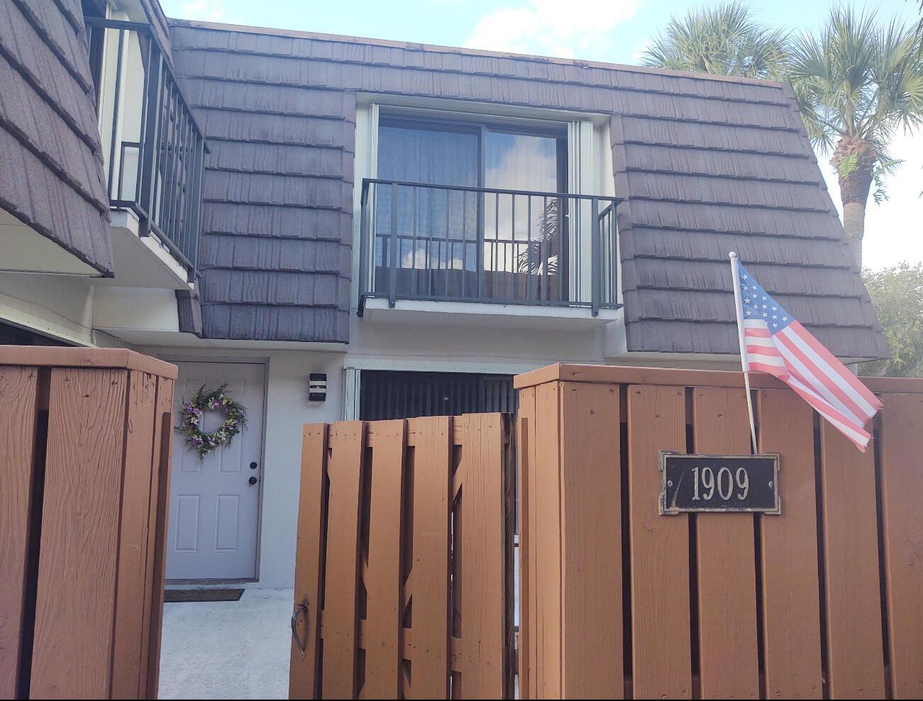 A two-story townhouse exterior features a brown shingled roof, a balcony, and a wooden fence — 1909 19th Court # 33a, Jupiter FL 33477, JUPITER, FL