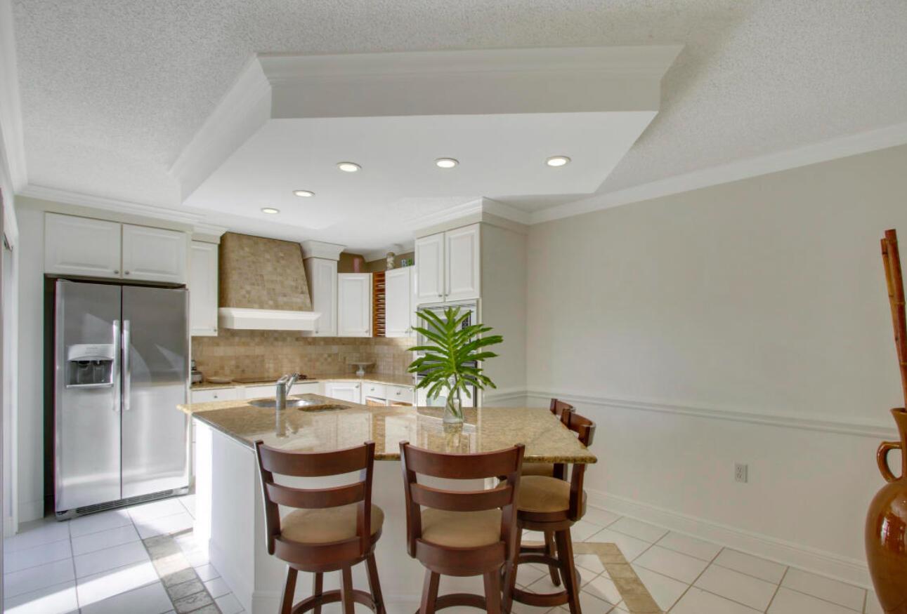 A kitchen features white cabinets, granite countertops, a central island with bar stools, and recessed lighting — 1909 19th Court # 33a, Jupiter FL 33477, JUPITER, FL