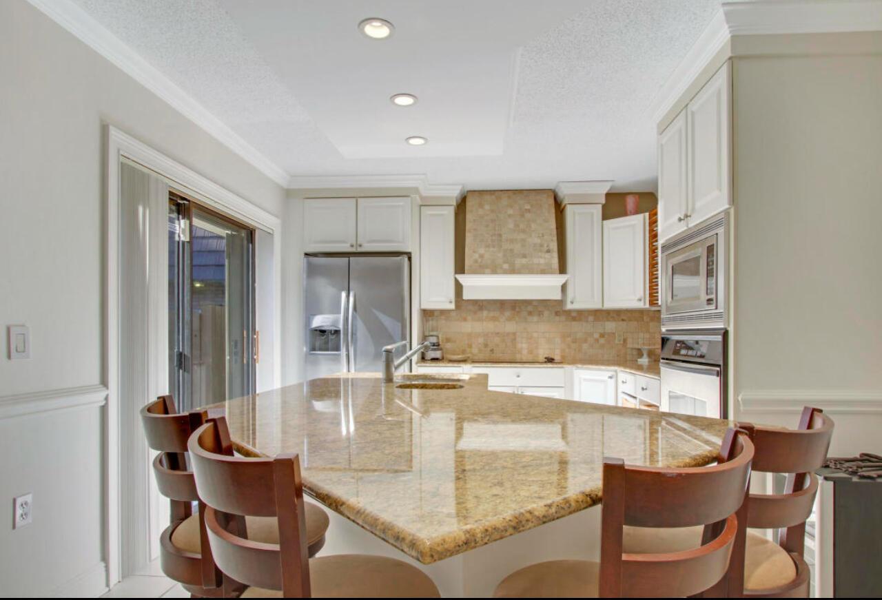 A kitchen features a granite island with bar seating, white cabinets, and stainless steel appliances — 1909 19th Court # 33a, Jupiter FL 33477, JUPITER, FL