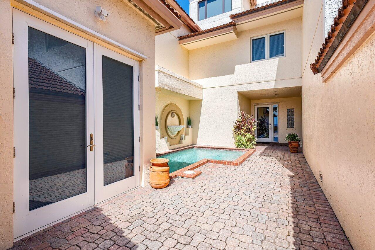 A small courtyard features a pool, a wall fountain, and brick pavers between two buildings — 4517 S Ocean Boulevard, Highland Beach FL 33487, HIGHLAND BEACH, FL