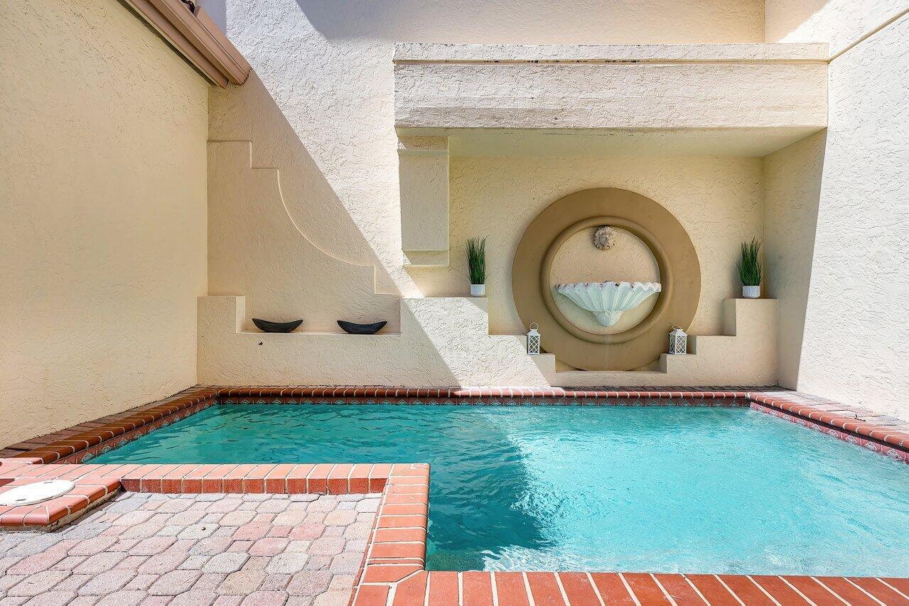 A small swimming pool sits in a courtyard with a wall-mounted fountain and stucco walls — 4517 S Ocean Boulevard, Highland Beach FL 33487, HIGHLAND BEACH, FL