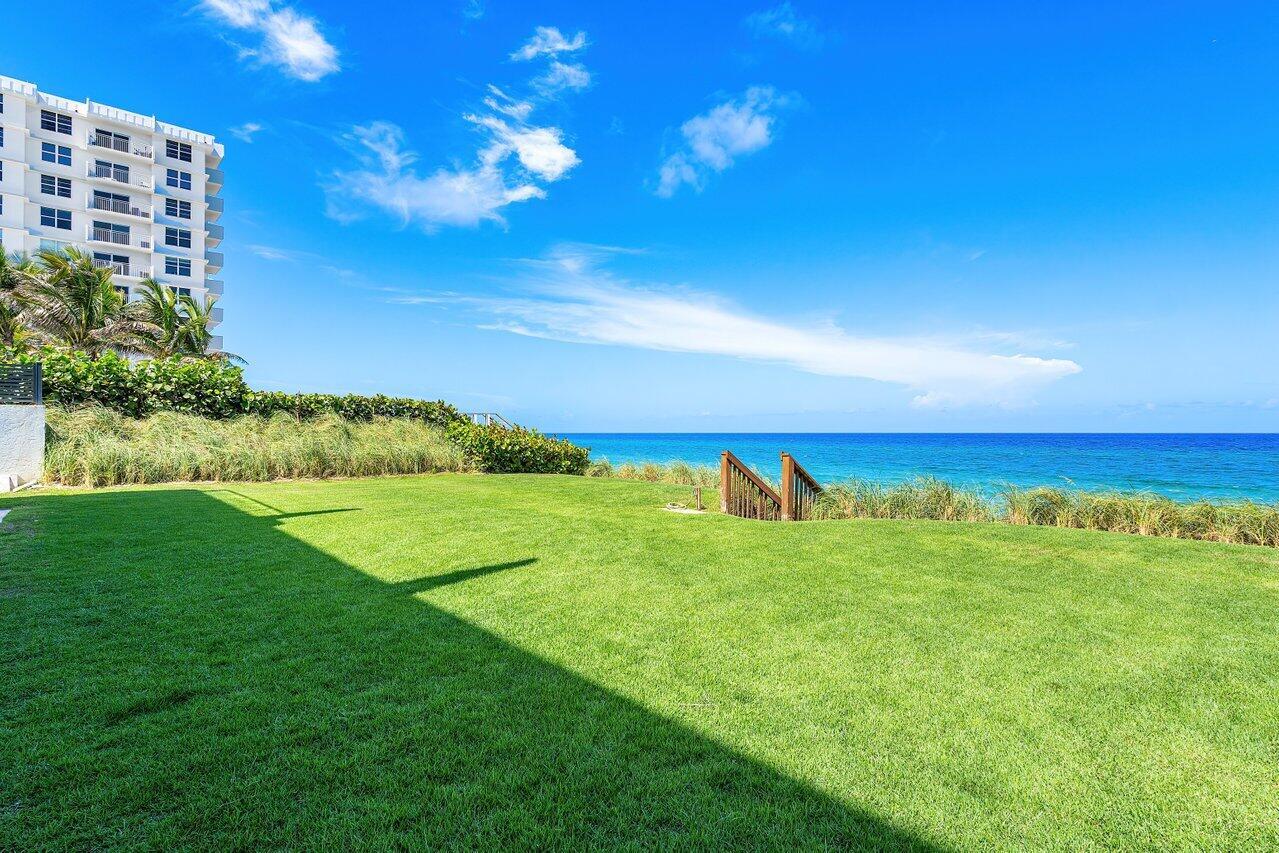 A grassy lawn overlooks the ocean with a multi-story building on the left — 4517 S Ocean Boulevard, Highland Beach FL 33487, HIGHLAND BEACH, FL