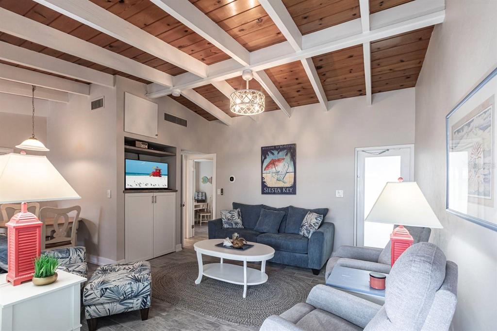 A living room features a wood-paneled vaulted ceiling with white beams and a blue sofa — 6006 MIDNIGHT PASS ROAD UNIT 22, SARASOTA, FL