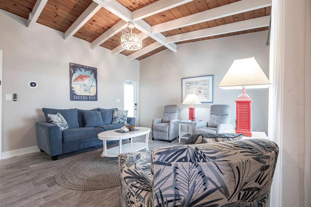 A living room features a blue sofa, two recliners, and a wood-beamed vaulted ceiling — 6006 MIDNIGHT PASS ROAD UNIT 22, SARASOTA, FL