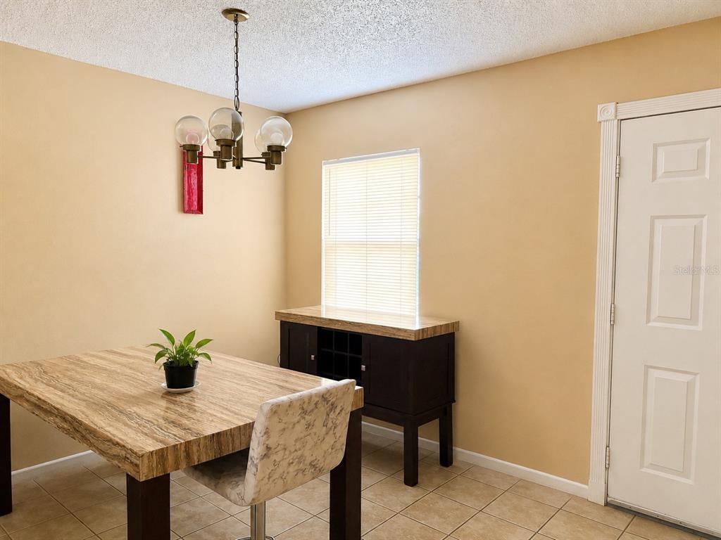 A dining room features a stone-topped table, a matching sideboard, and a multi-globe chandelier — 7011 WATERSIDE DR, TAMPA, FL