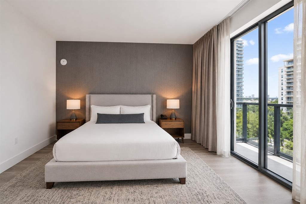 A bedroom features a bed with a gray headboard, two nightstands, and a balcony view — 229 SW 9TH STREET UNIT 406, MIAMI, FL