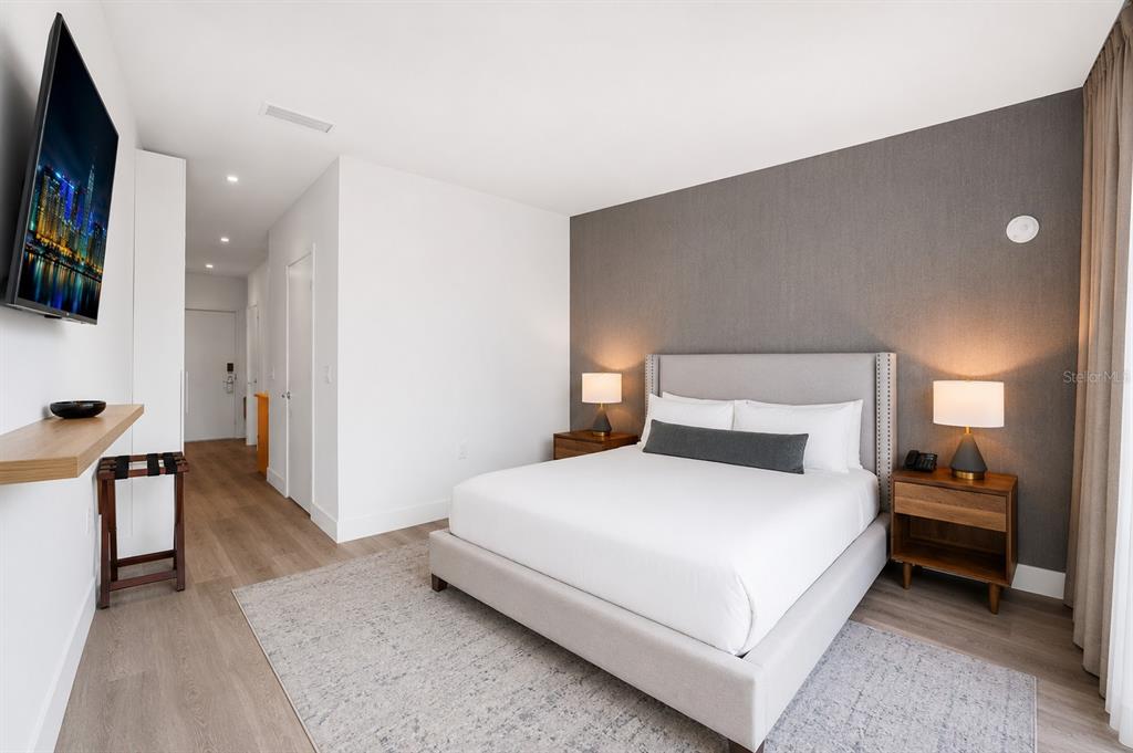 A modern bedroom features a queen bed, gray accent wall, and a wall-mounted television — 229 SW 9TH STREET UNIT 406, MIAMI, FL