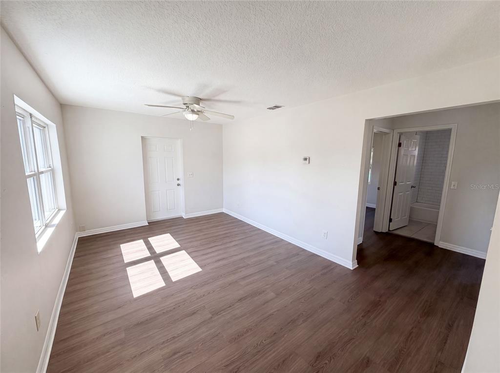An empty room with wood-look flooring, a ceiling fan, and a doorway leading to a bathroom — 1604 PARK AVENUE, MELBOURNE, FL