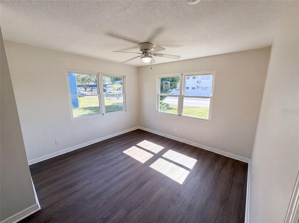 An empty bedroom with wood-look flooring, a ceiling fan, and windows on two walls — 1604 PARK AVENUE, MELBOURNE, FL